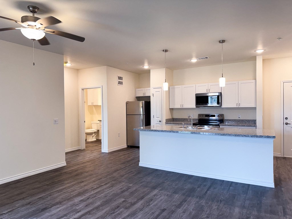 A spacious kitchen with a bar counter and a ceiling fan.