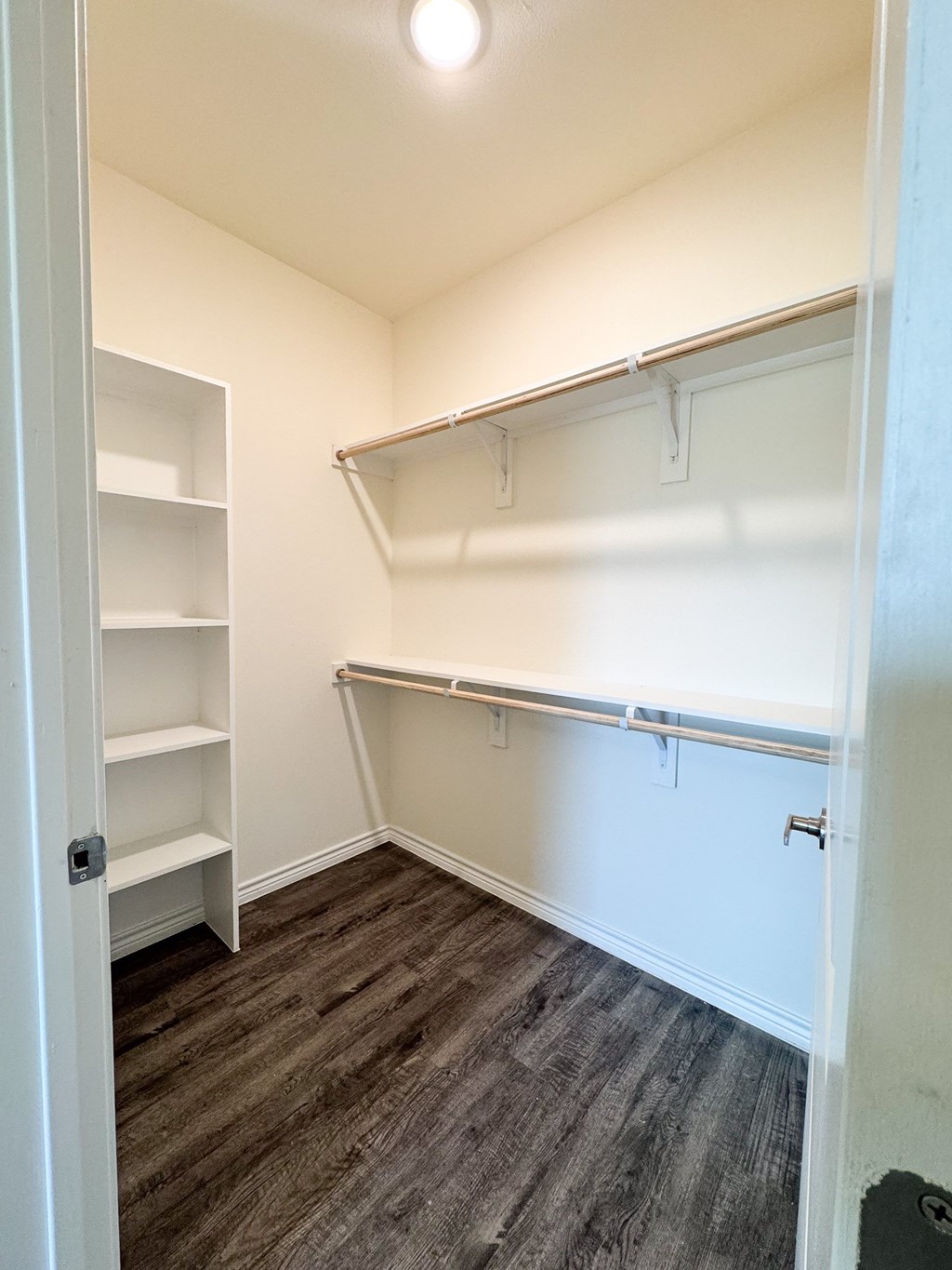 A small, empty room with a shelving unit and a door.