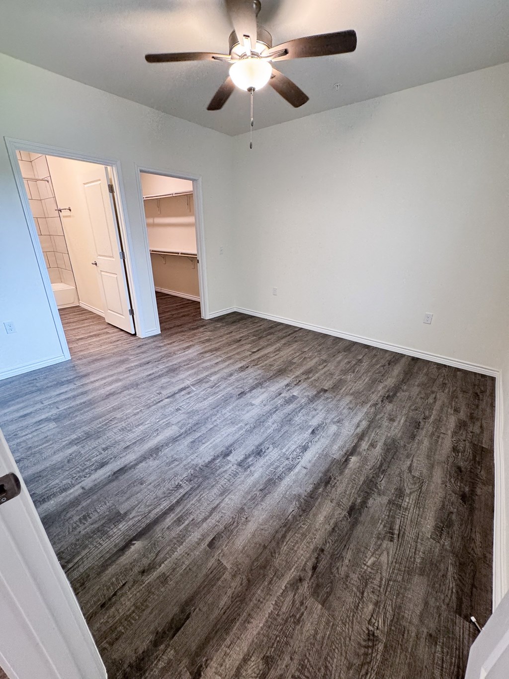 A room with a ceiling fan and a door leading to another room.