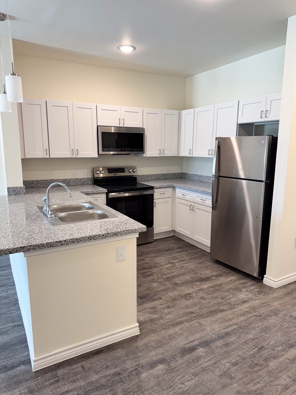 A kitchen with a stainless steel refrigerator, microwave, and oven.