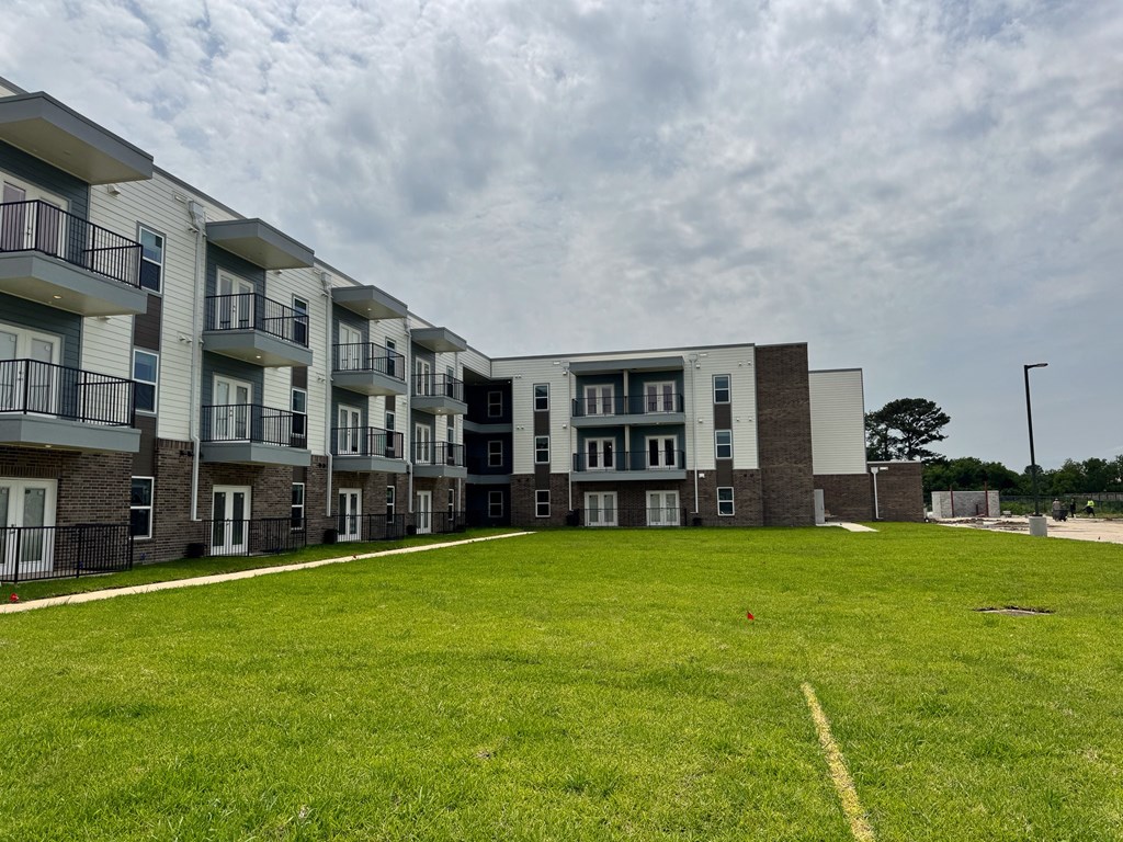 Apartment complex with a grassy area in front.