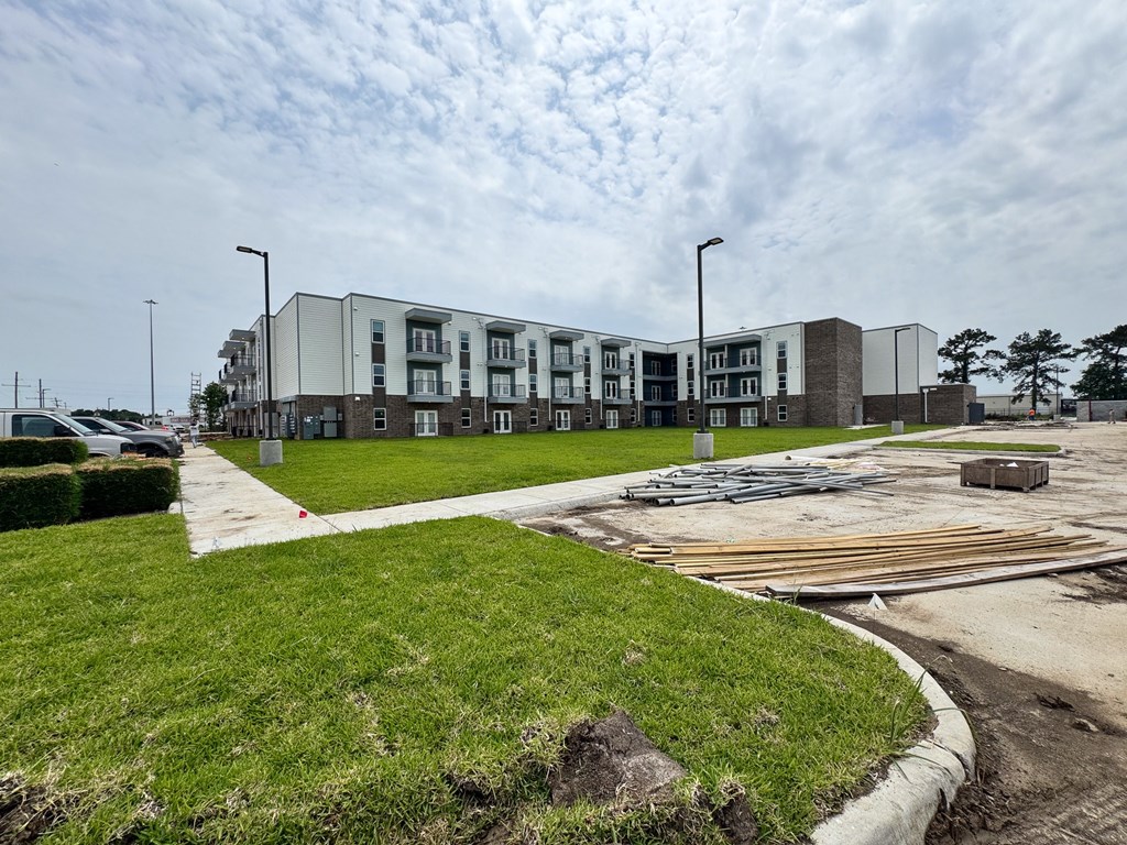 A modern apartment complex with a grassy area in front.
