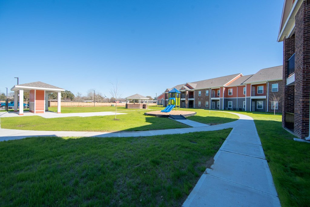 a playground with a slide in the middle of a grassy area