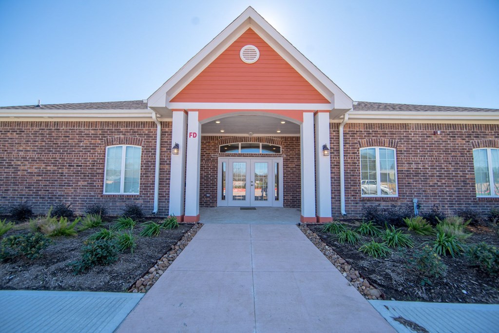 a brick building with a red roof and white pillars