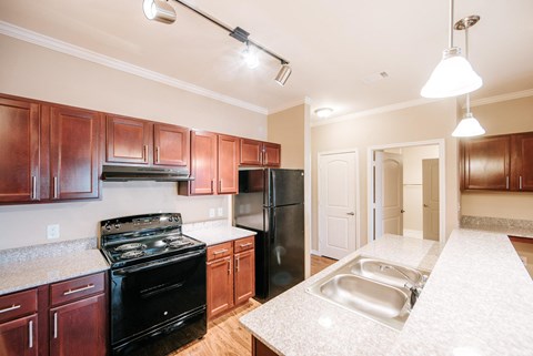 A kitchen with brown cabinets and black appliances.