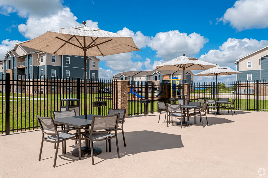 a patio with tables and umbrellas at the enclave at woodbridge apartments in sugar land