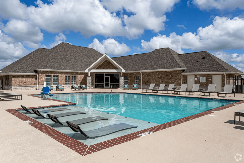 a large swimming pool with lounge chairs and a building in the background