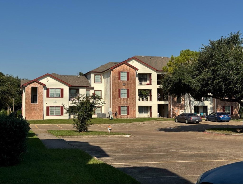 Apartment complex with a parking lot in front.