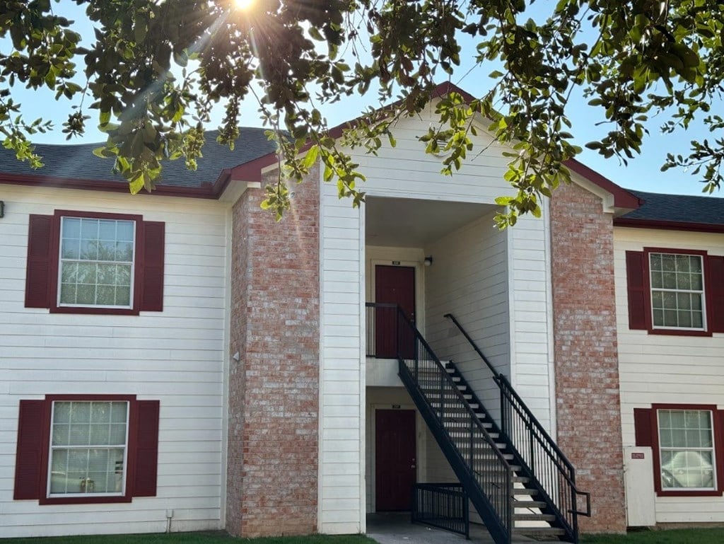 A white house with red shutters and a black staircase.