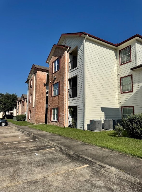 A white apartment building with a brick facade stands next to a white one.