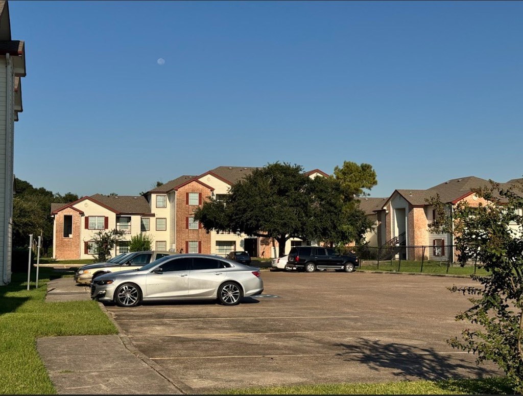 A silver car is parked in a parking lot in front of a building.