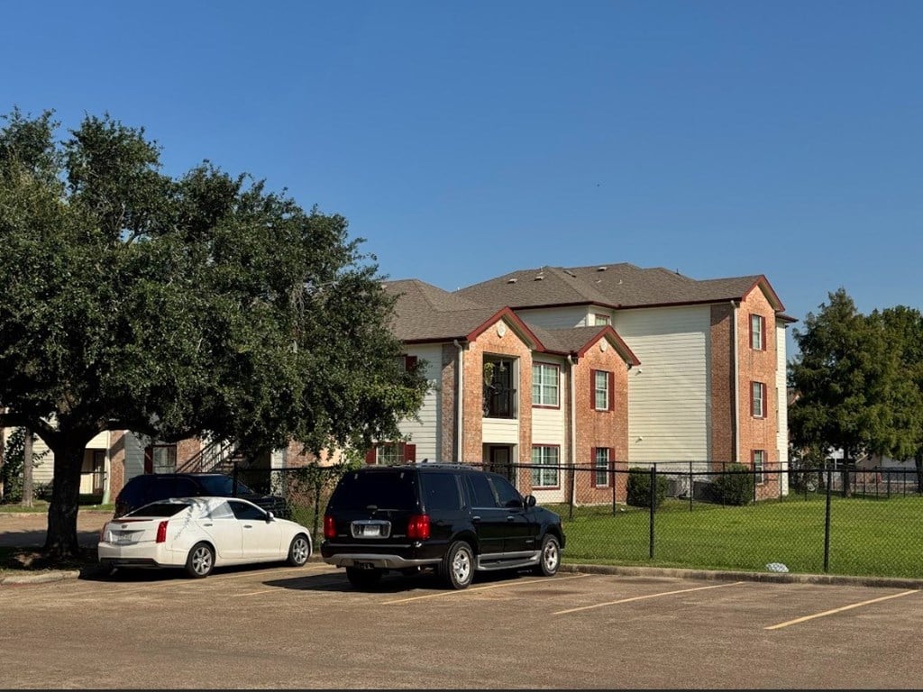 A black car is parked in a parking lot in front of a building.