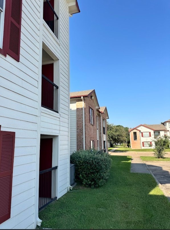 A white building with red shutters and a green bush in front.
