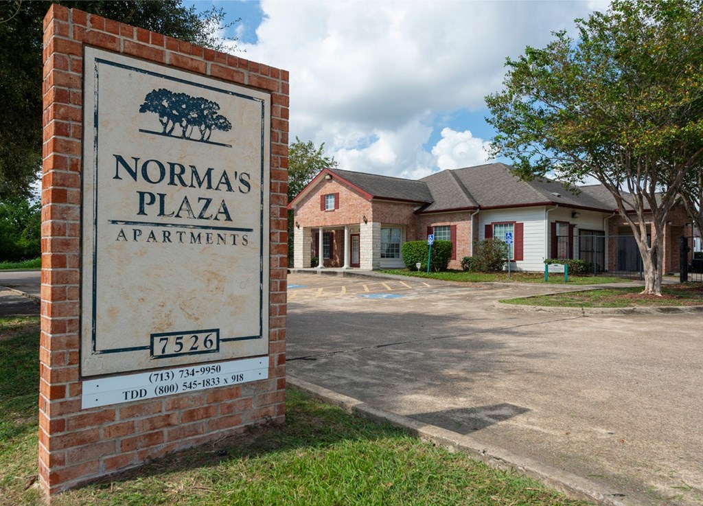 A sign for Norma's Plaza Apartments stands in front of the building.