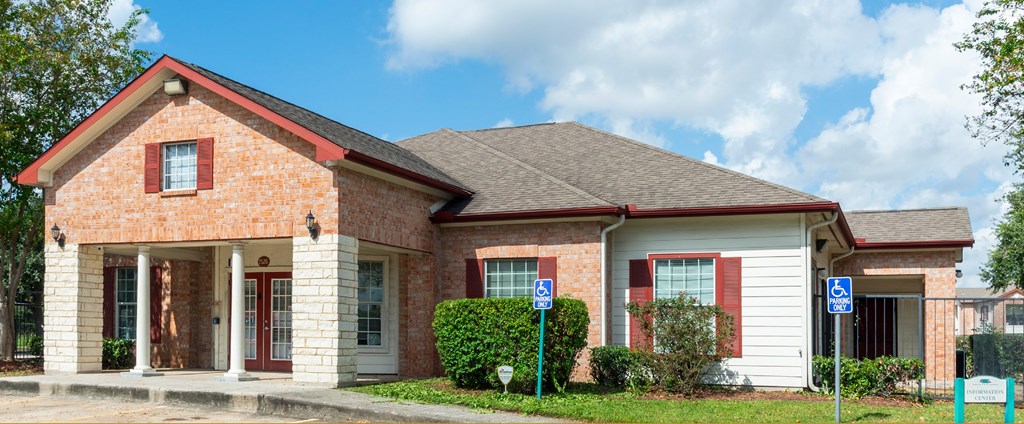 A brick house with a red roof and a sign on the front.