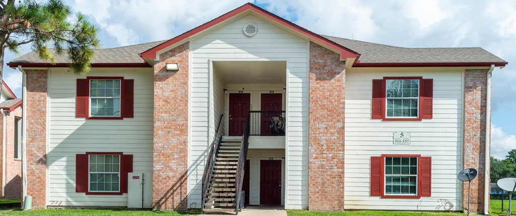A white house with red shutters and a red door.