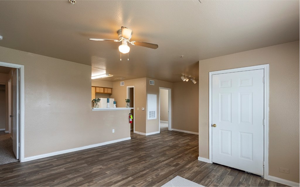 A room with a ceiling fan and wooden floors.