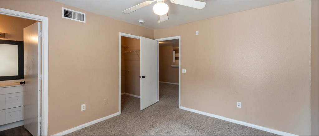 A room with a ceiling fan and a mirror on the wall.
