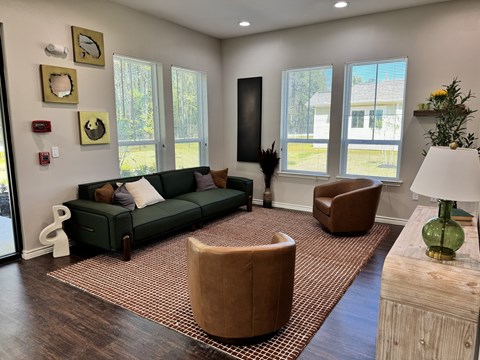 A living room with a green couch, brown armchair, and a wooden coffee table.