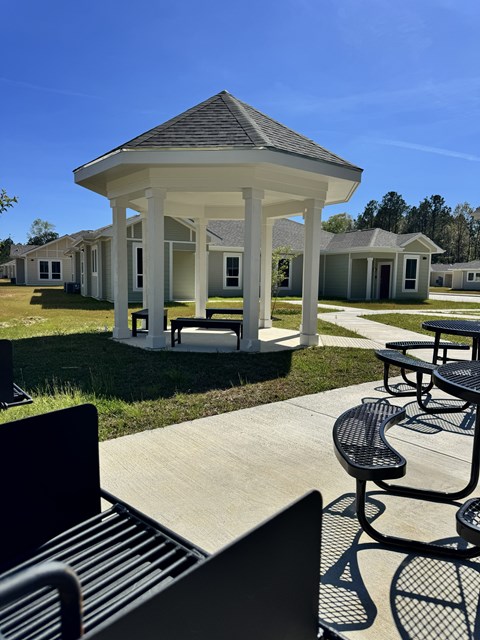 A gazebo is surrounded by benches in a park.