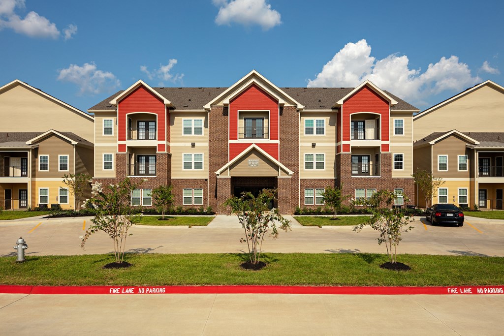an exterior view of an apartment building with a parking lot