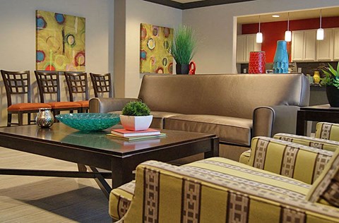 A living room with a brown couch and a glass table.