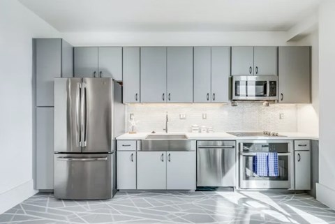 A modern kitchen with a stainless steel refrigerator and a microwave above the sink.