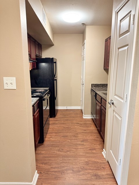 A kitchen with a black fridge and wooden floors.
