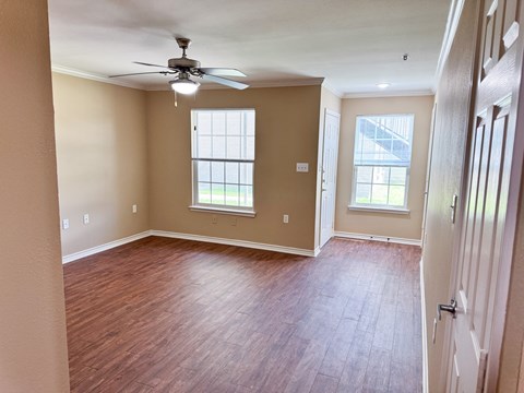 A room with a ceiling fan and wooden flooring.