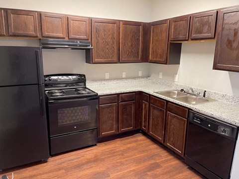 A kitchen with wooden cabinets and black appliances.