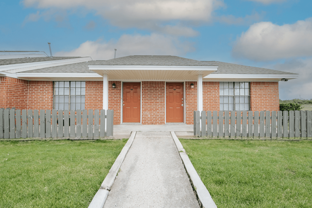 a house with red doors and a white picket fence