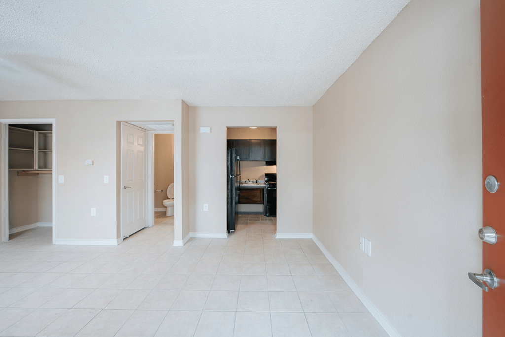 a living room with a tiled floor and a kitchen in the background
