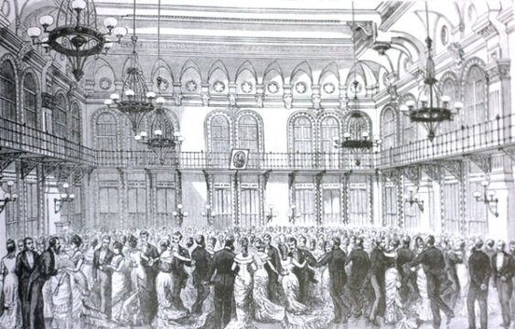 A black and white image of a large group of people in a grand hall.