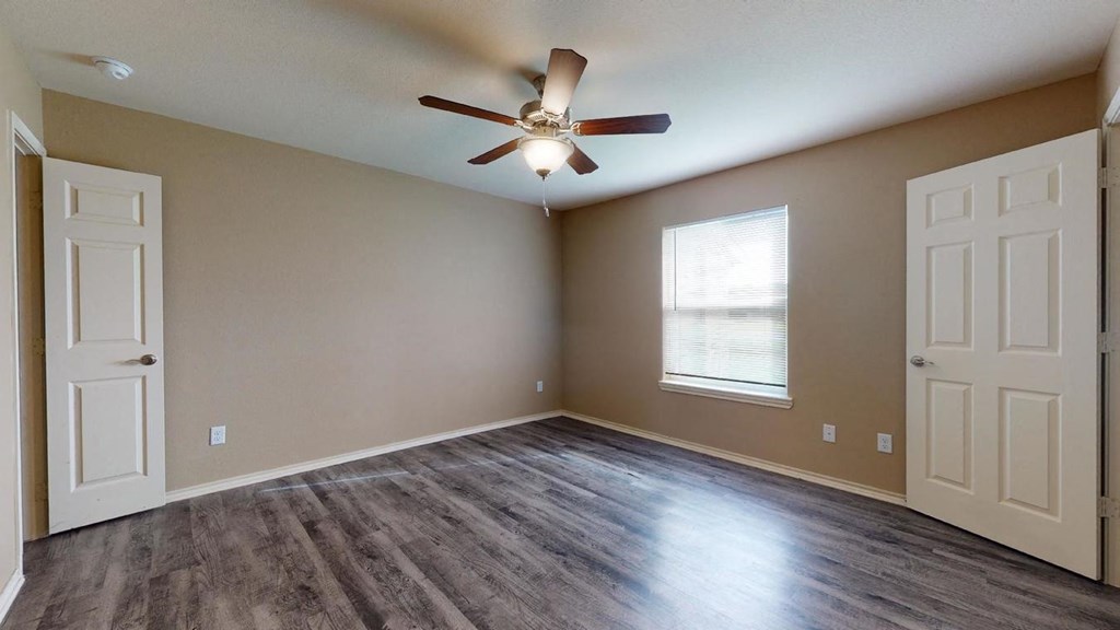 an empty living room with a ceiling fan and a window