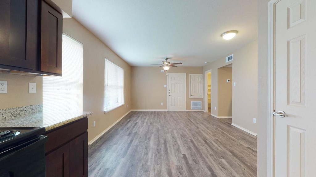an empty living room and kitchen with a ceiling fan