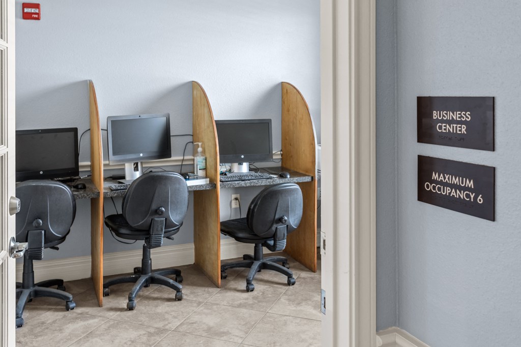 a business center with three desks with computer monitors and chairs