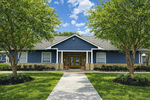 A blue building with a yellow door and two trees in front.