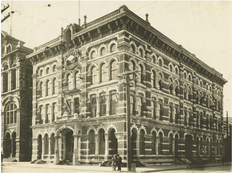 A black and white photo of a large, ornate building with a clock on the front.
