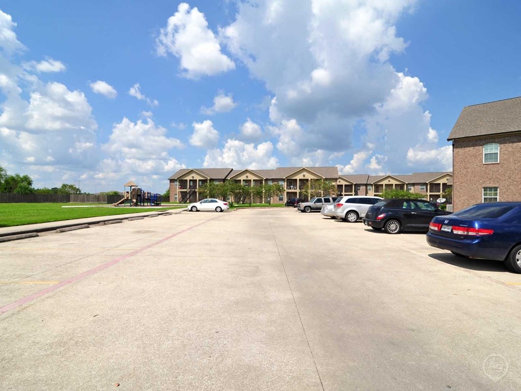 a parking lot with cars in front of apartment buildings