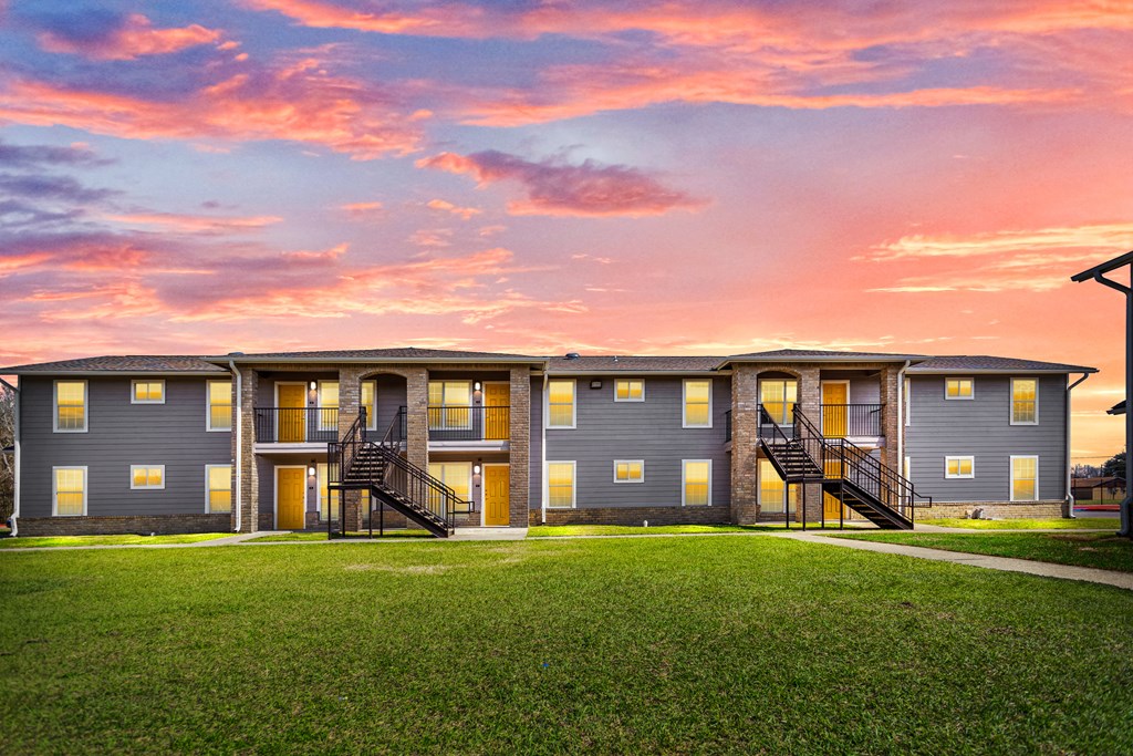 a row of condominiums at sunset with a pink sky