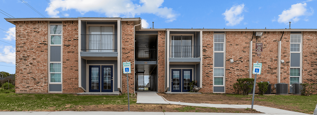 a brick apartment building with a sidewalk in front of it