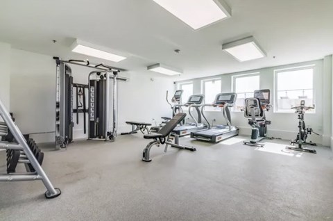 A spacious gym with a variety of equipment including treadmills, elliptical machines, and weight machines.