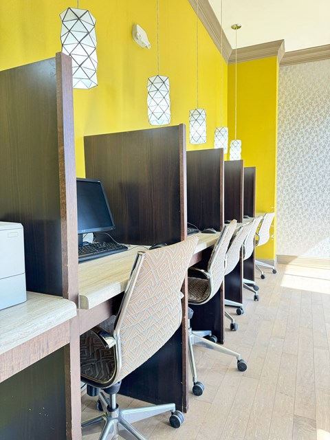 A row of chairs with a patterned cushion are in front of a yellow wall.