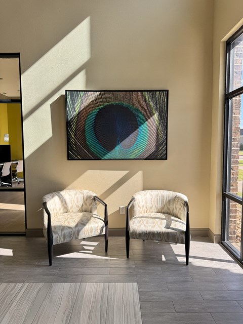 Two chairs are placed in front of a painting.