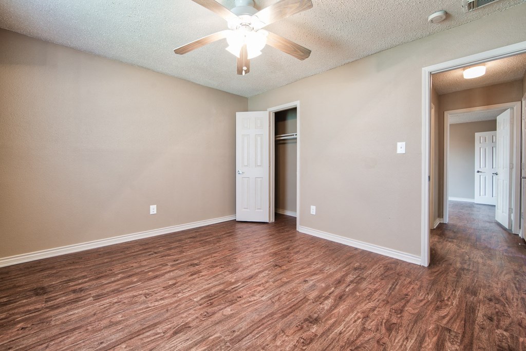 an empty living room with wood flooring and a ceiling fan