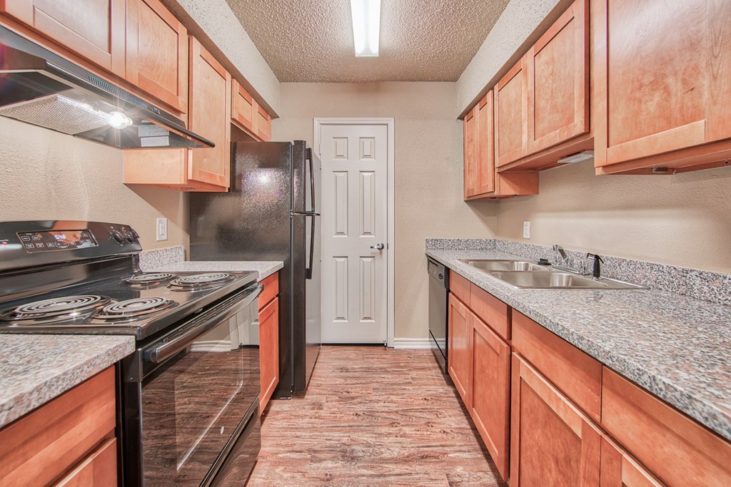 a kitchen with wood cabinets and granite counter tops and a black refrigerator