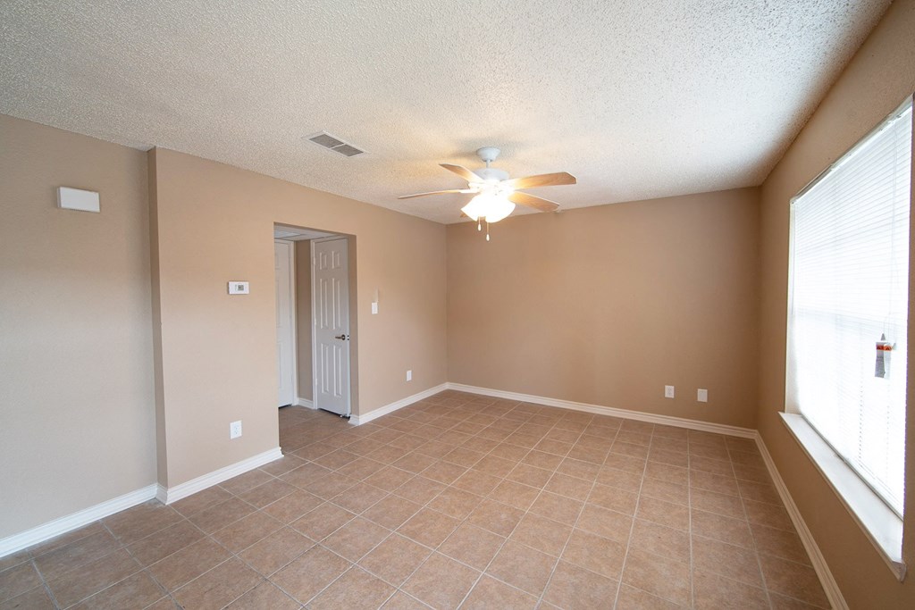 an empty living room with a ceiling fan and a window