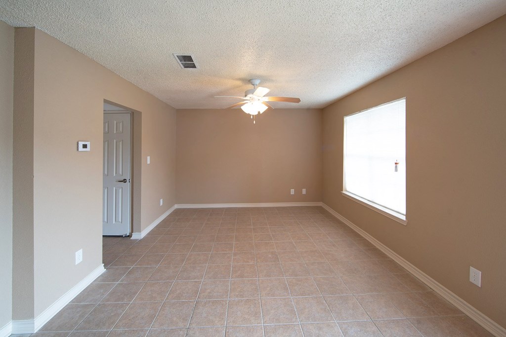 an empty living room with a ceiling fan and a window