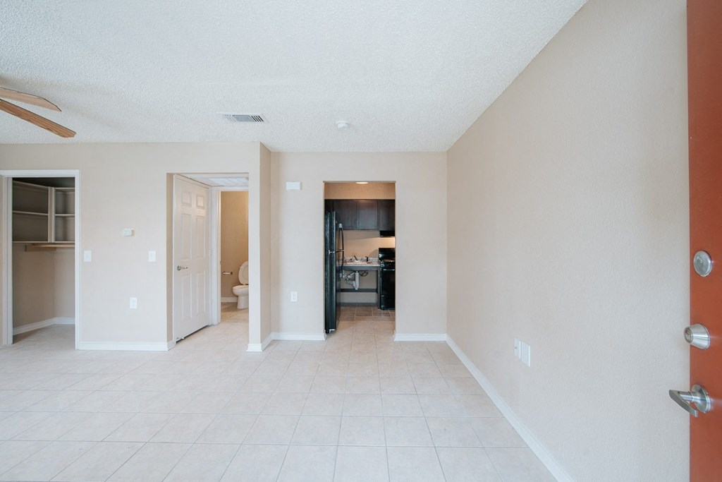 a living room with a tiled floor and a kitchen in the background
