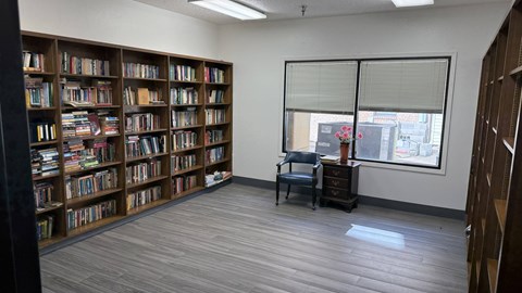 A room with a large bookshelf filled with books and a chair in front of it.